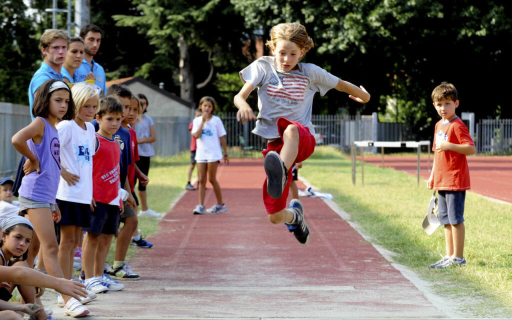 Ragazzino che fa salto in lungo per il campionato di raccolta fondi Dai Como